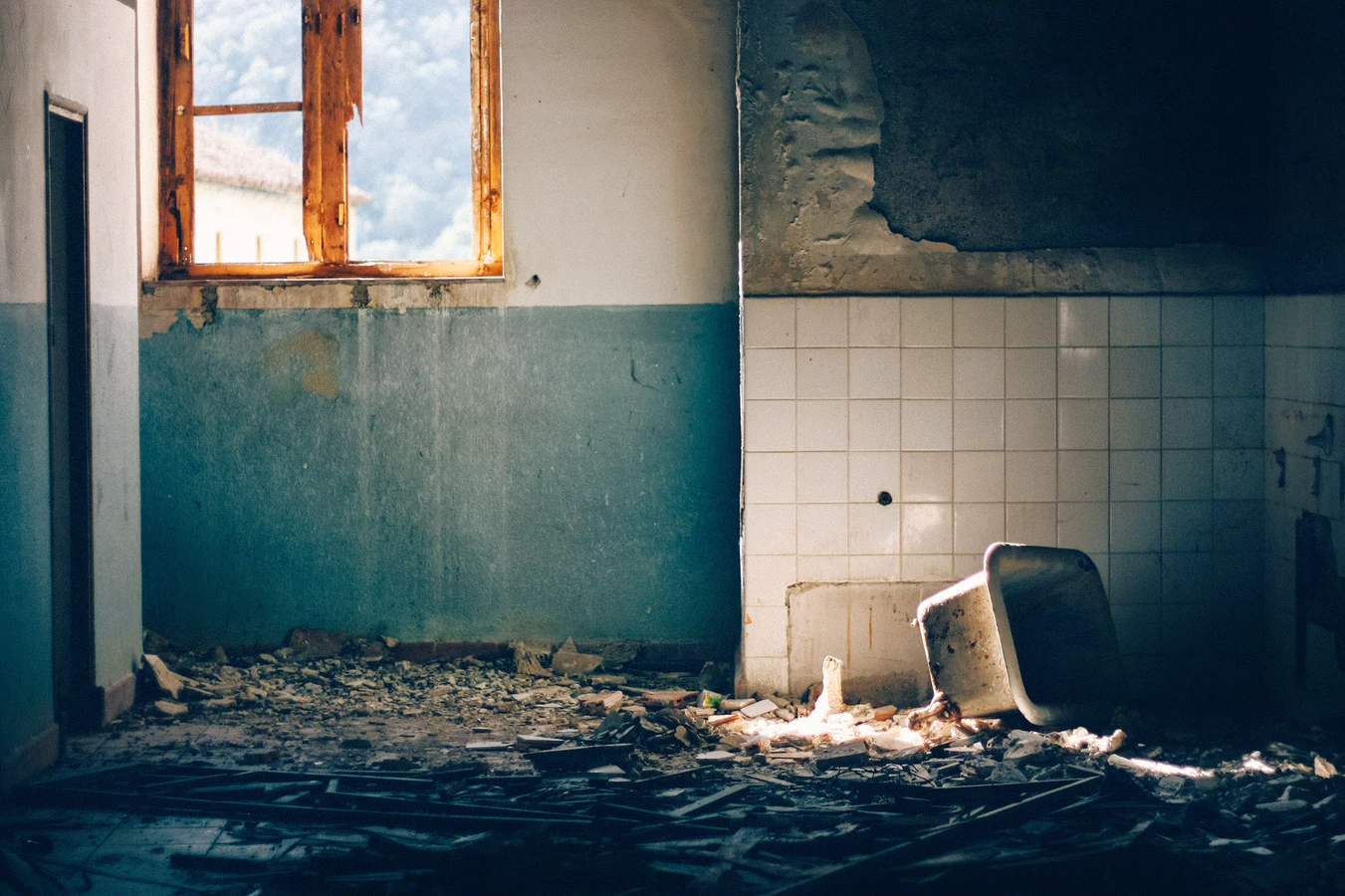 an old abandoned bathroom with smashed tiling and debris on the ground