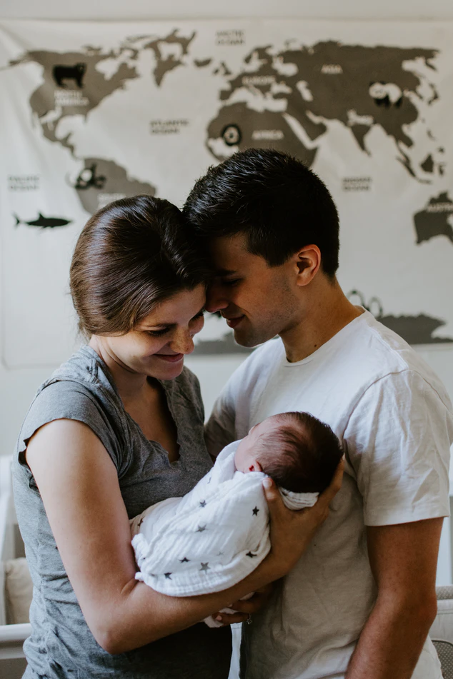 a man and women holding a newborn baby wrapped in white cloth