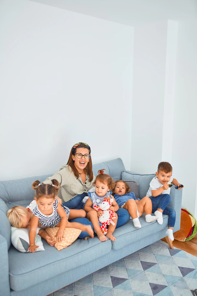 a women laughing on a blue couch with her five children
