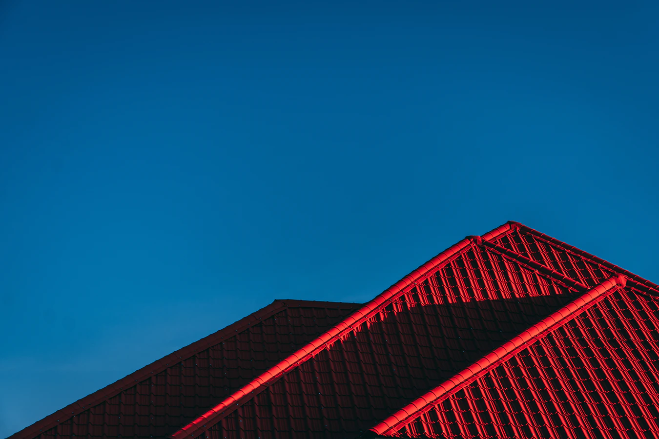a blue sky with red tiles on the roof of a house renovation project