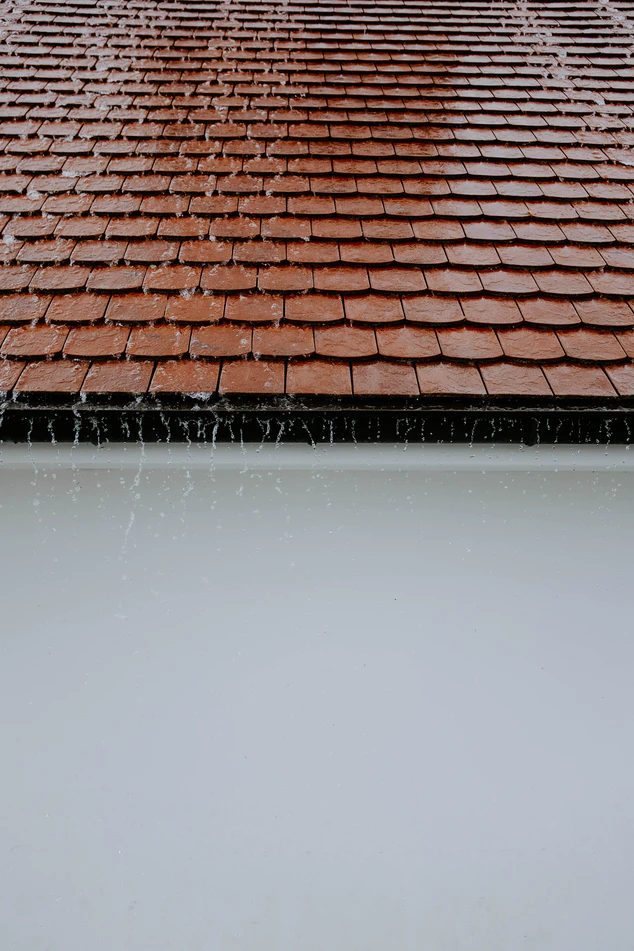 water dripping off a set of orange layered roof tiles