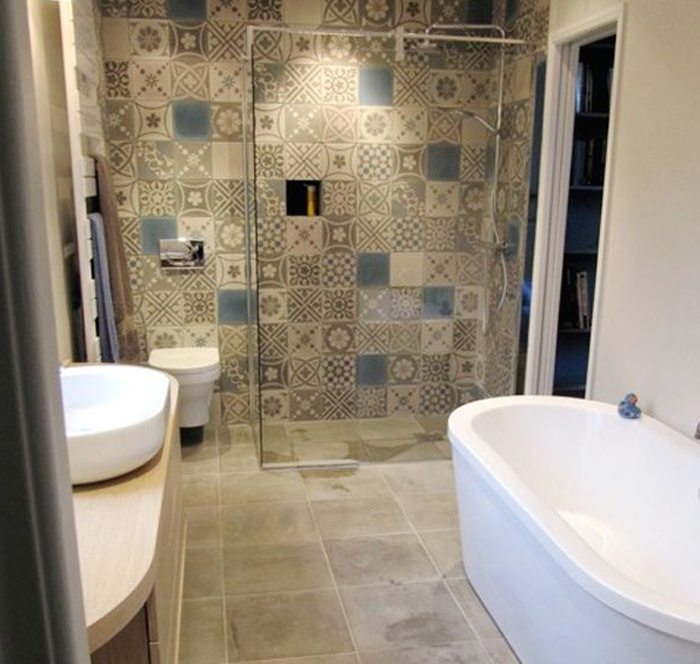 Mosaic tiled bathroom with a white ceramic toilet and sink.
