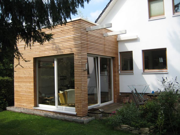 Wooden home extension with glass windows on a white house in a garden